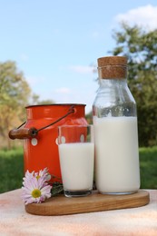 Photo of Tasty fresh milk on color textured table outdoors