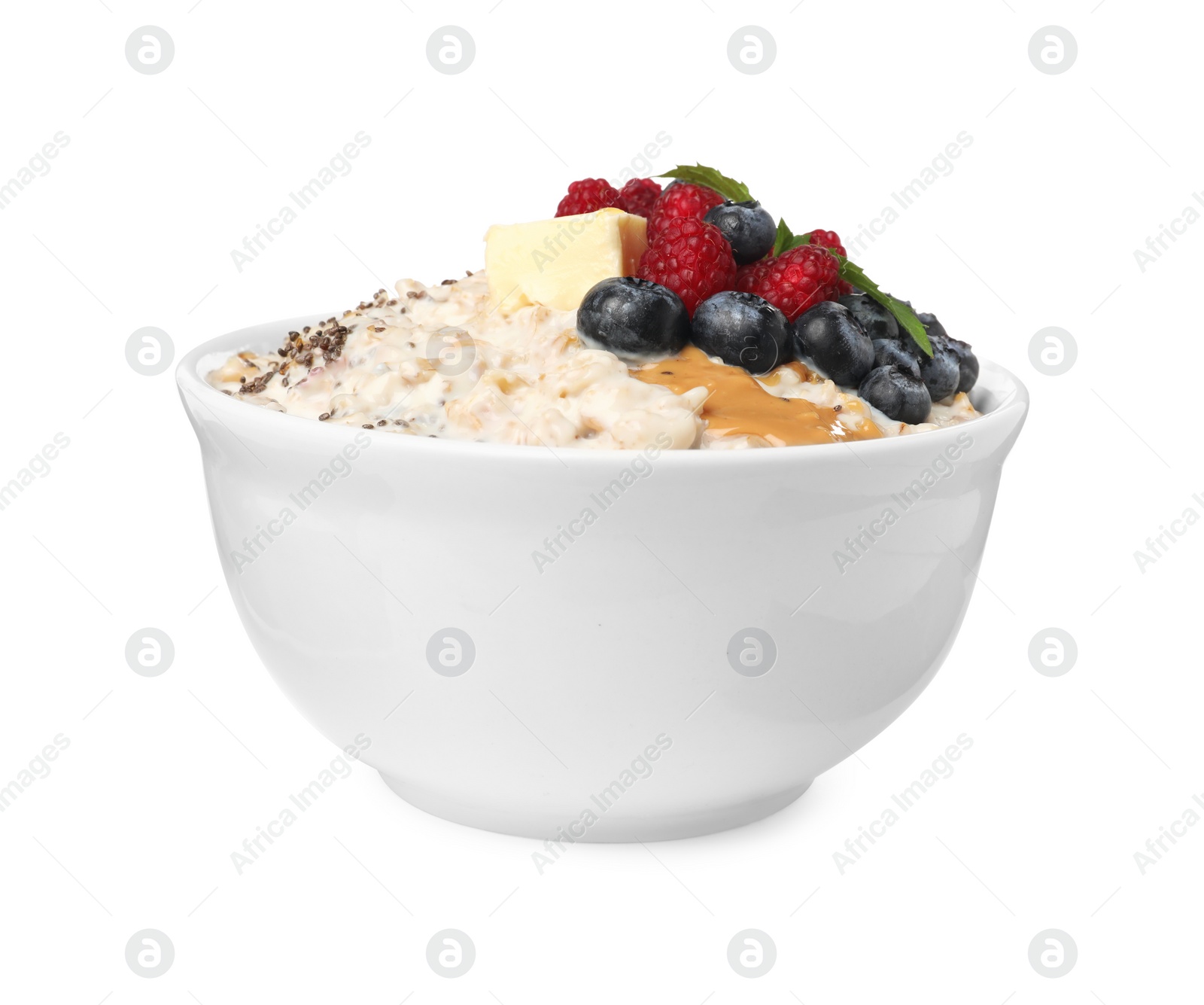 Photo of Tasty boiled oatmeal with berries, chia seeds and peanut butter in bowl isolated on white