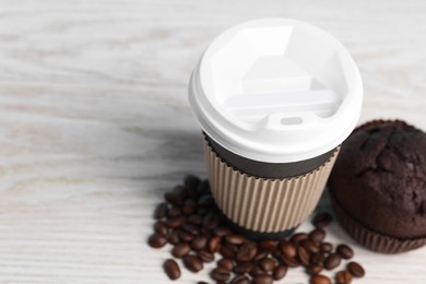 Photo of Paper cup, coffee beans and muffin on white wooden table, closeup with space for text. Coffee to go