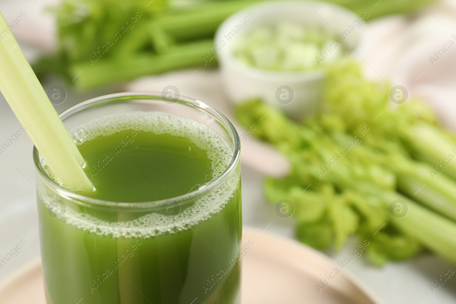 Photo of Glass of delicious celery juice and vegetables on table, closeup