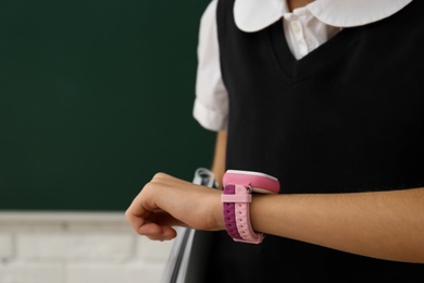 Photo of Girl with stylish smart watch in classroom, closeup