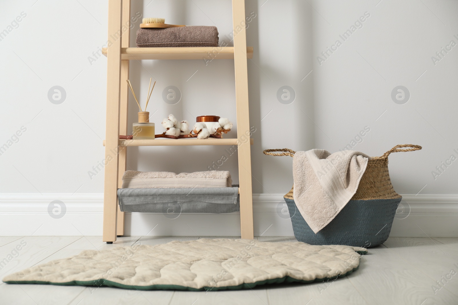 Photo of Wooden shelving unit with toiletries near white wall indoors. Bathroom interior element