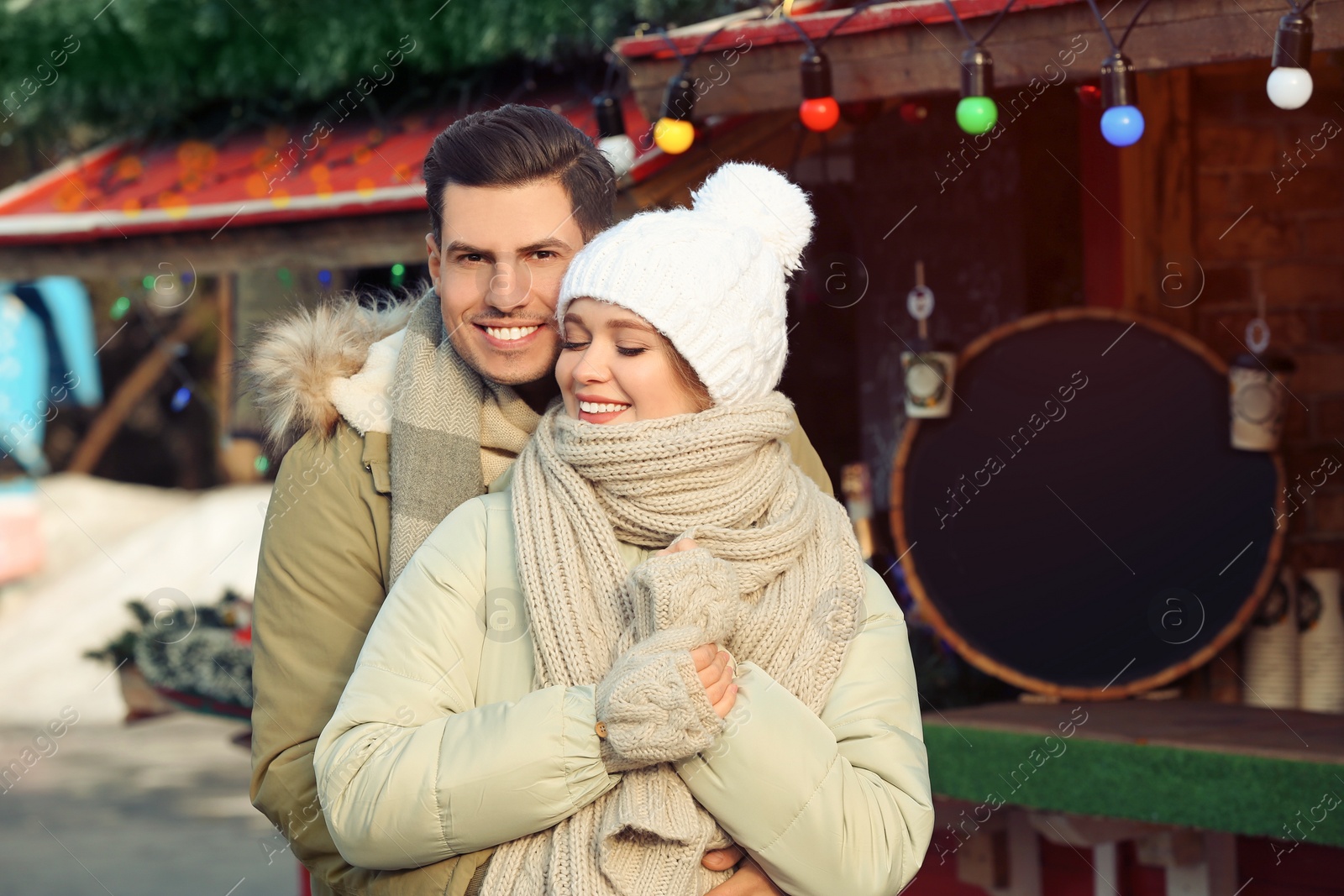 Photo of Happy couple in warm clothes at winter fair. Christmas season