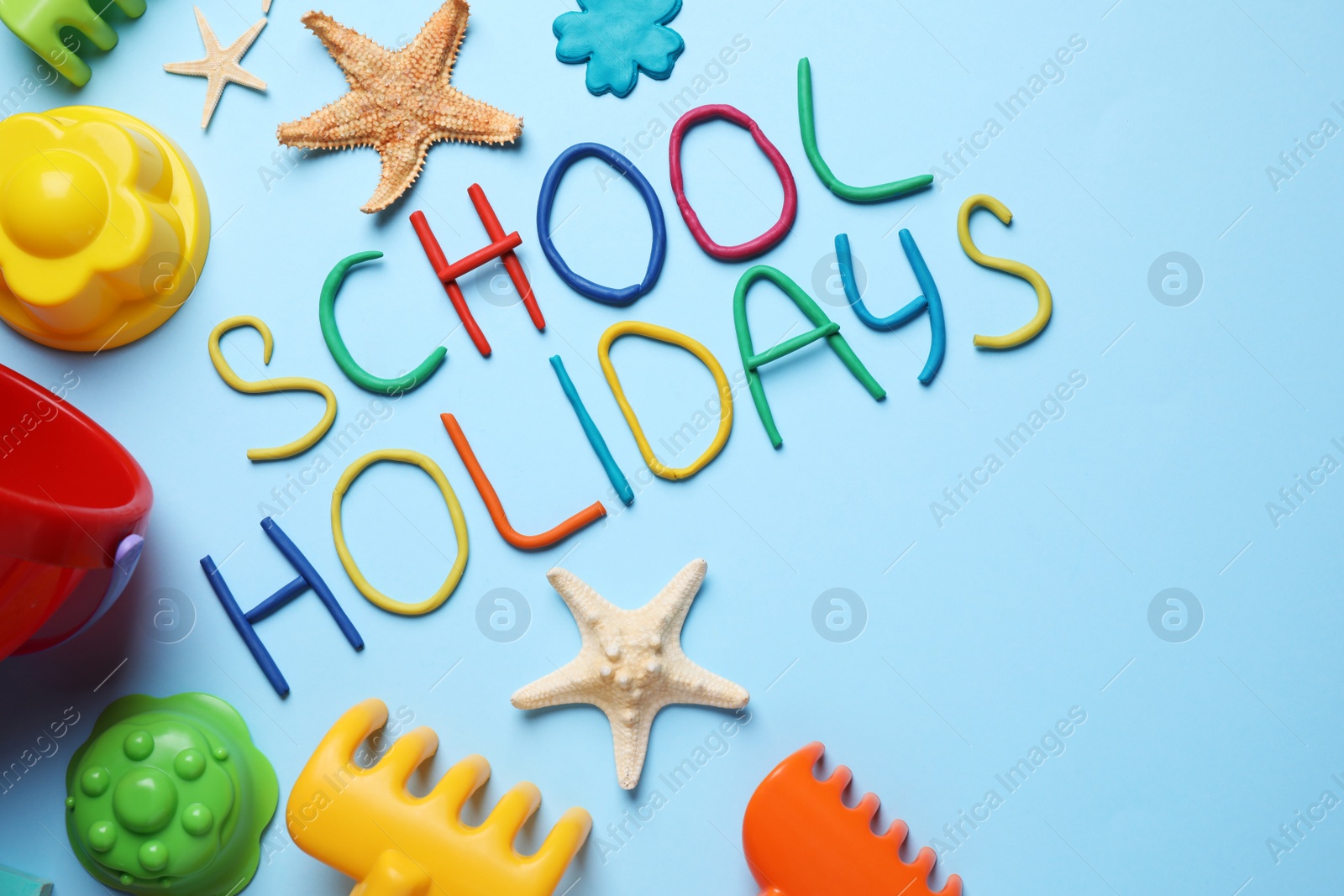 Photo of Flat lay composition with phrase School Holidays made of modeling clay on light blue background