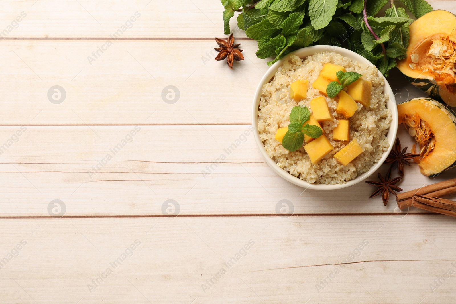 Photo of Flat lay composition with bowl of tasty quinoa porridge and pumpkin on light wooden table. Space for text