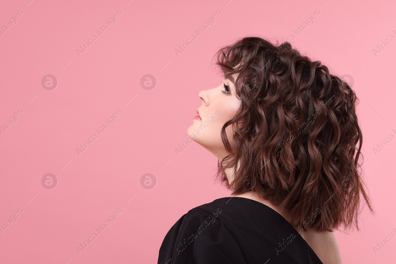 Photo of Beautiful young woman with wavy hairstyle on pink background. Space for text