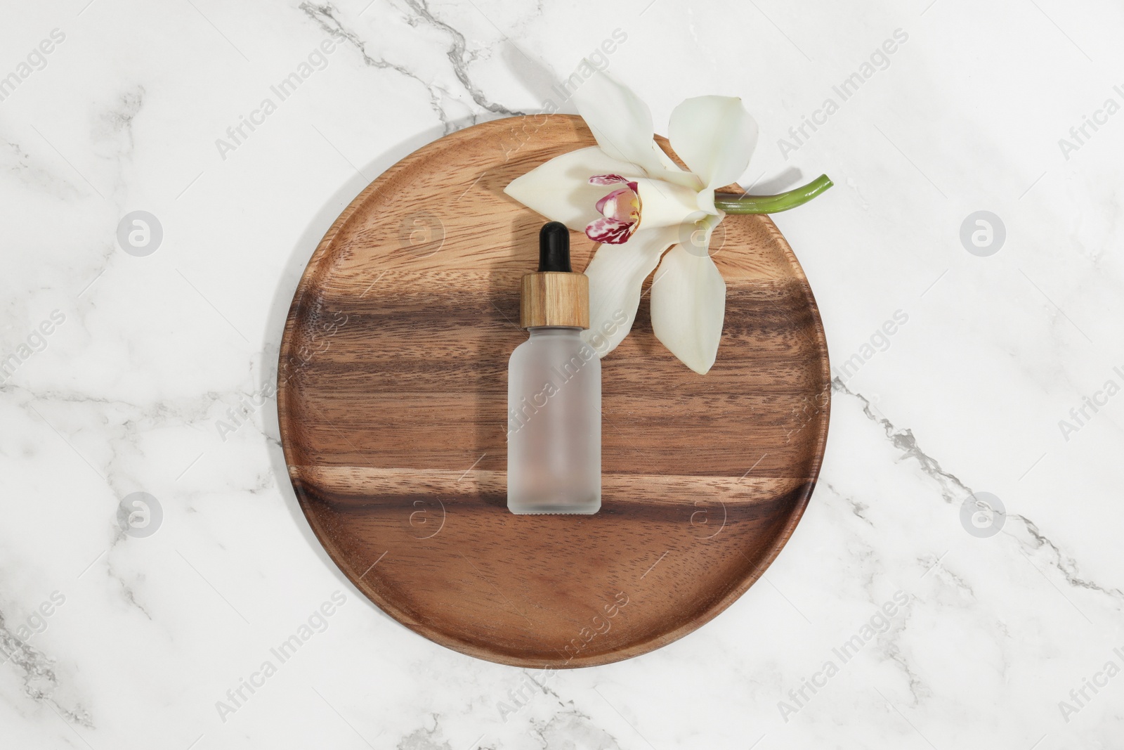 Photo of Bottle of cosmetic product and orchid flower on white marble table, top view