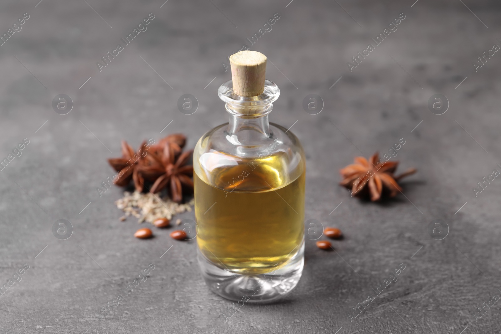 Photo of Anise essential oil and spices on grey table