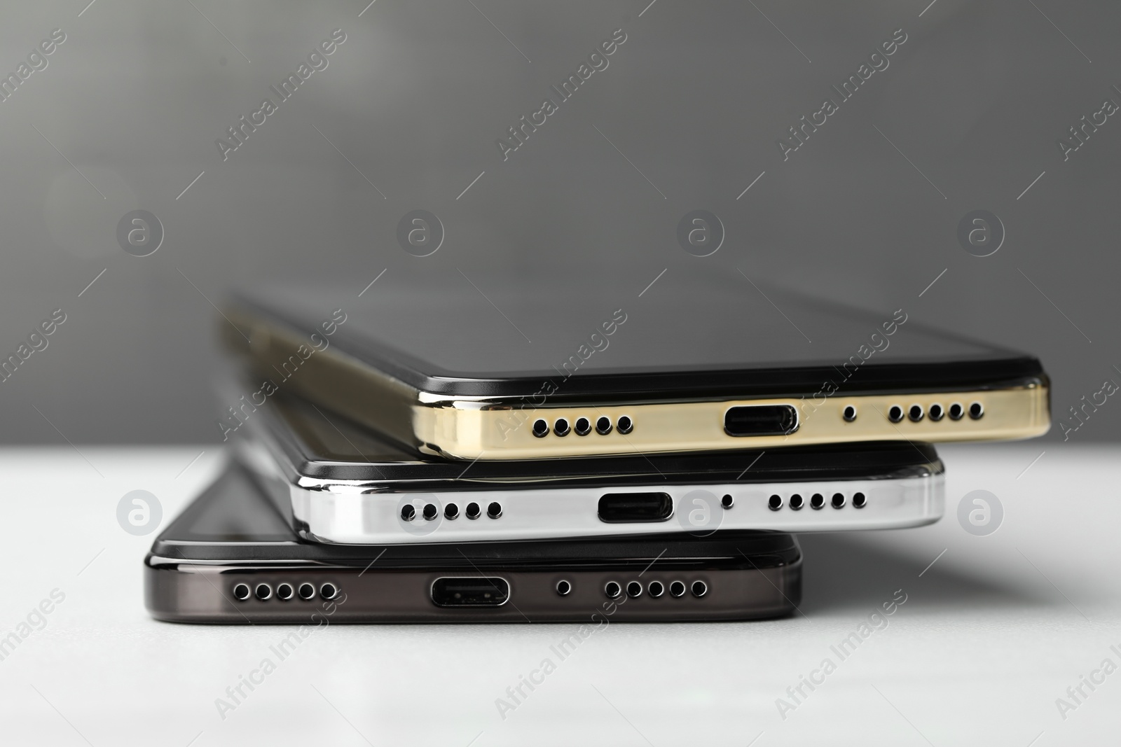 Photo of Stack of modern smartphones on white table, closeup