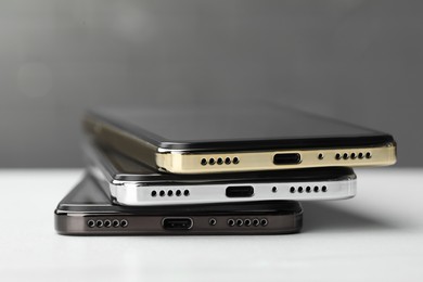 Photo of Stack of modern smartphones on white table, closeup