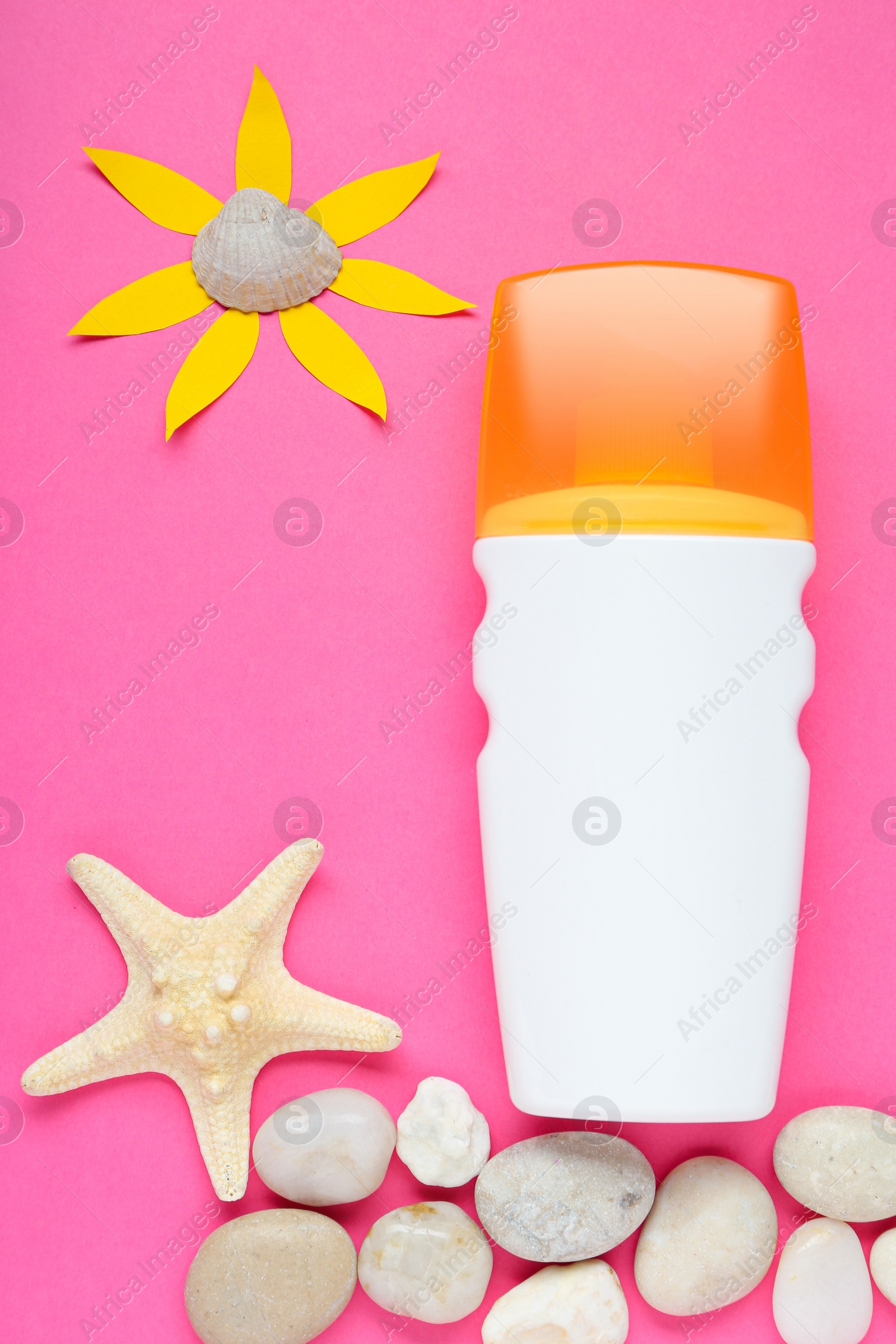 Photo of Suntan cream, sun made of paper and seashells on pink background, flat lay