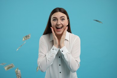 Photo of Excited woman under money shower on light blue background