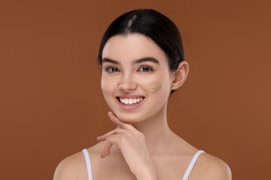 Photo of Teenage girl with swatch of foundation on face against brown background