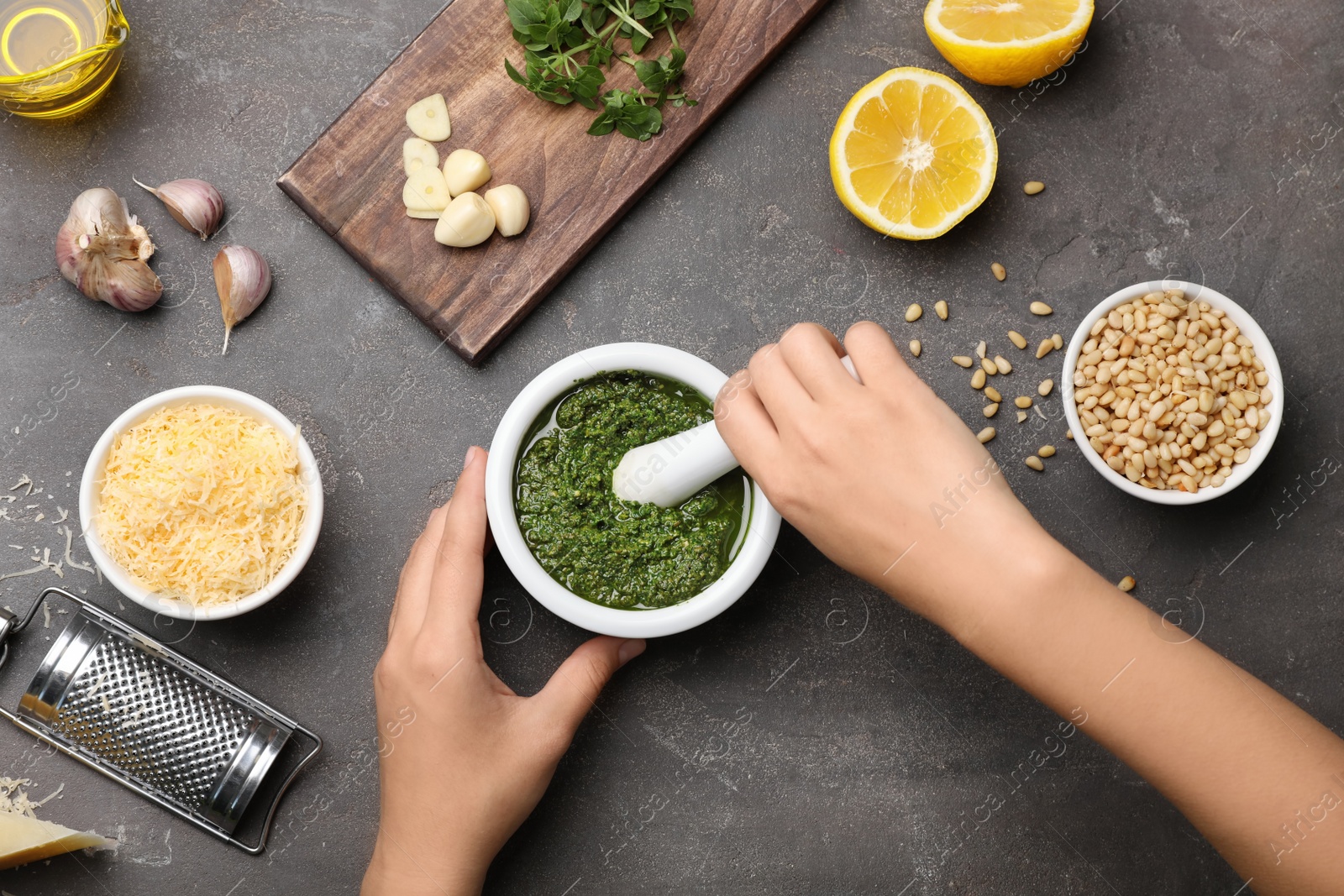 Photo of Woman preparing homemade basil pesto sauce on table, top view