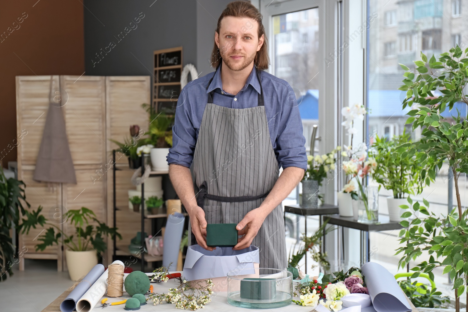 Photo of Male florist creating floral composition at workplace