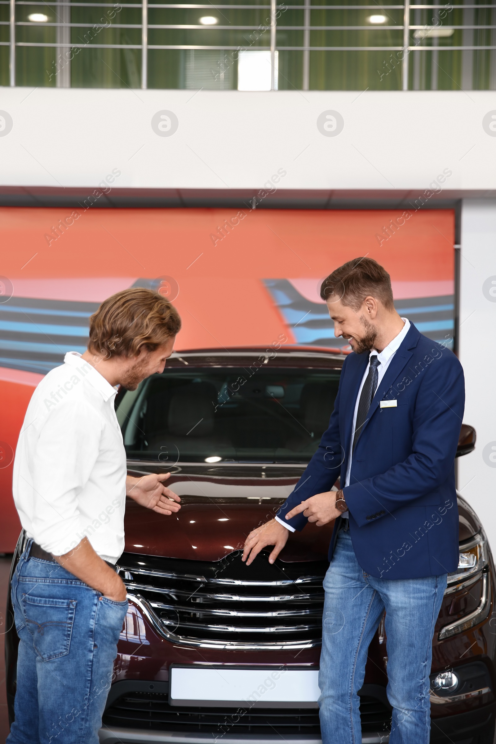 Photo of Salesman with customer in modern car dealership