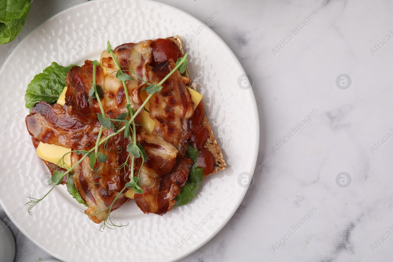 Photo of Tasty sandwich with bacon and microgreens on white marble table, top view. Space for text