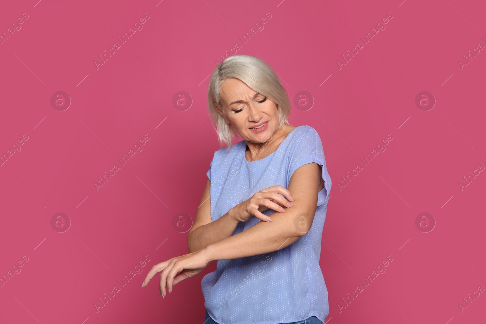 Photo of Mature woman scratching arm on color background. Annoying itch