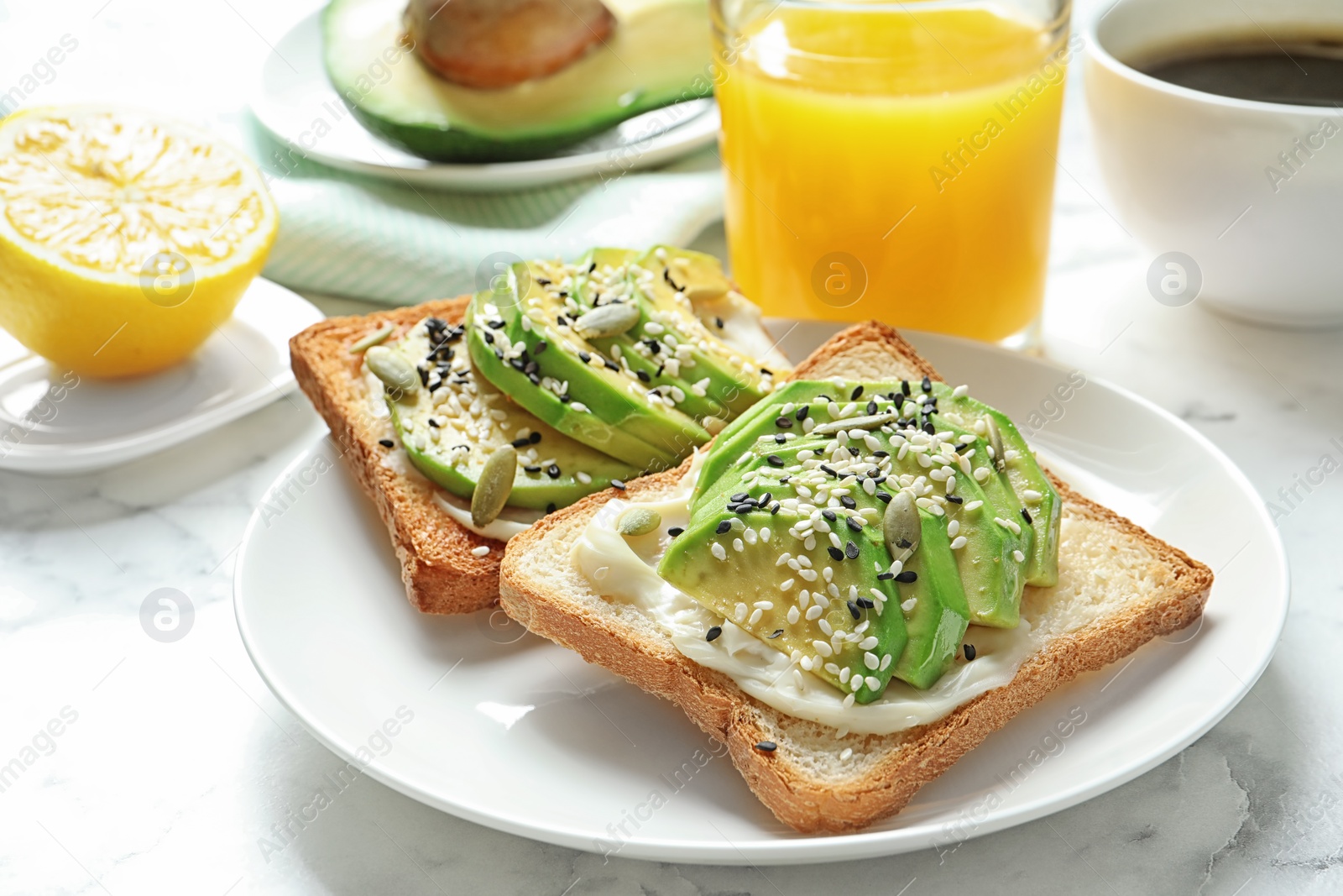 Photo of Toast bread with avocado and glass of juice on table