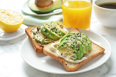 Toast bread with avocado and glass of juice on table