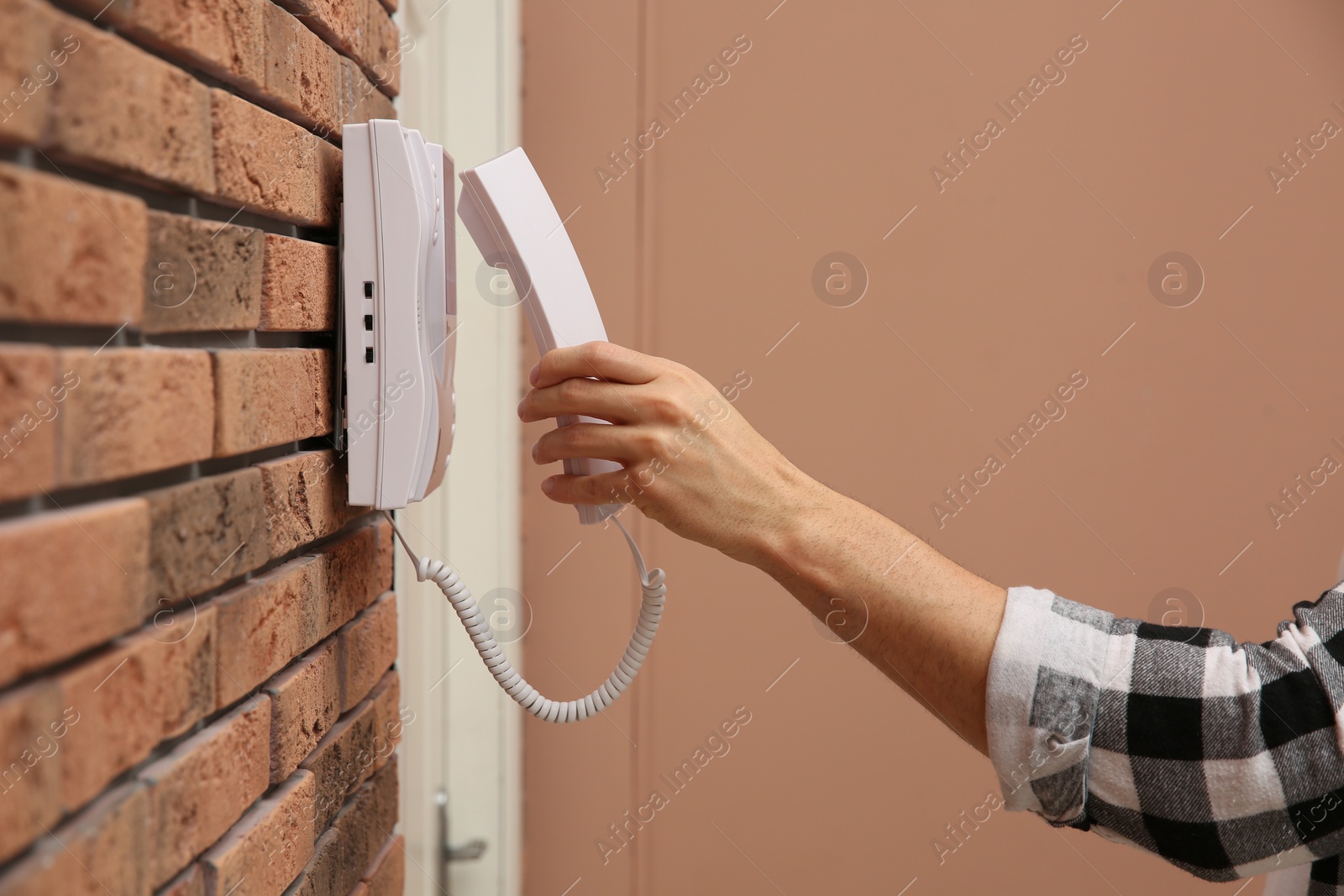 Photo of Man answering intercom call at home, closeup