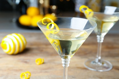 Glass of Lemon Drop Martini cocktail with zest on wooden table, closeup