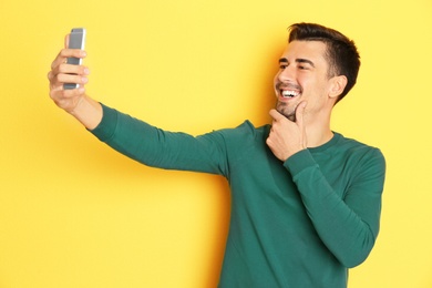 Photo of Young handsome man taking selfie against color background