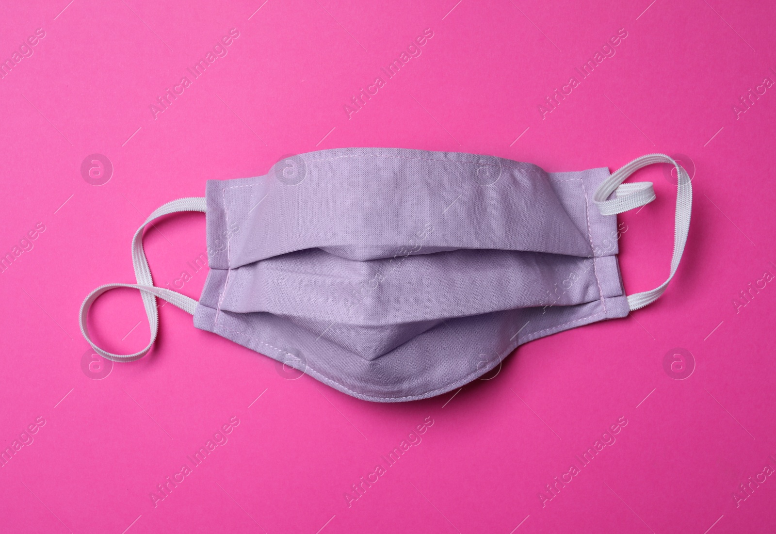 Photo of Homemade protective mask on pink background, top view. Sewing idea