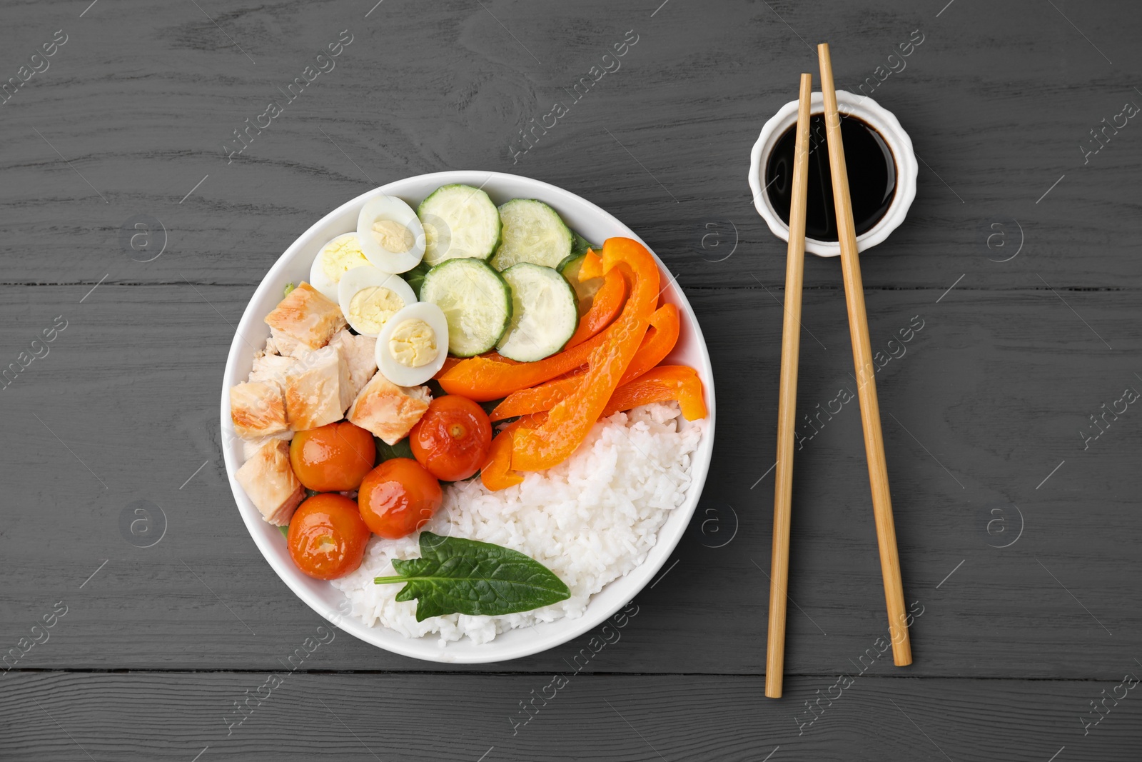 Photo of Delicious poke bowl with meat, rice, eggs and vegetables served on wooden table, flat lay