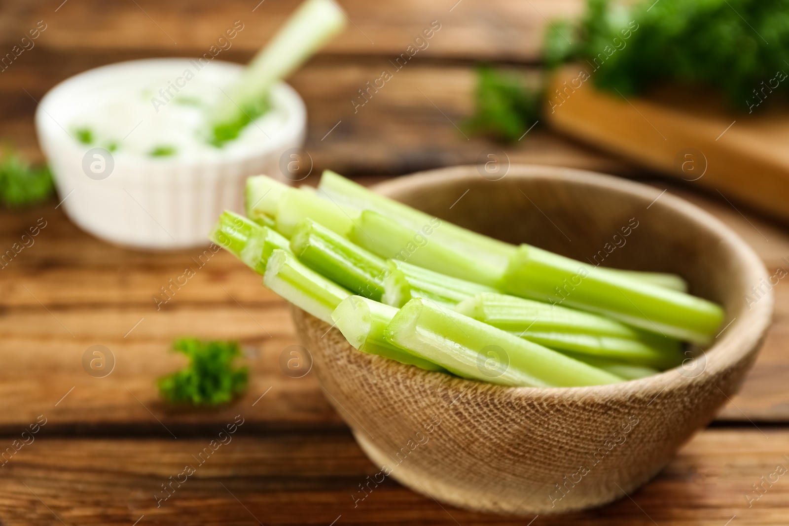 Photo of Celery sticks in wooden bowl on table, closeup