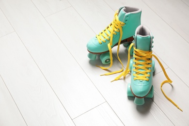 Photo of Pair of stylish quad roller skates on wooden background. Space for text