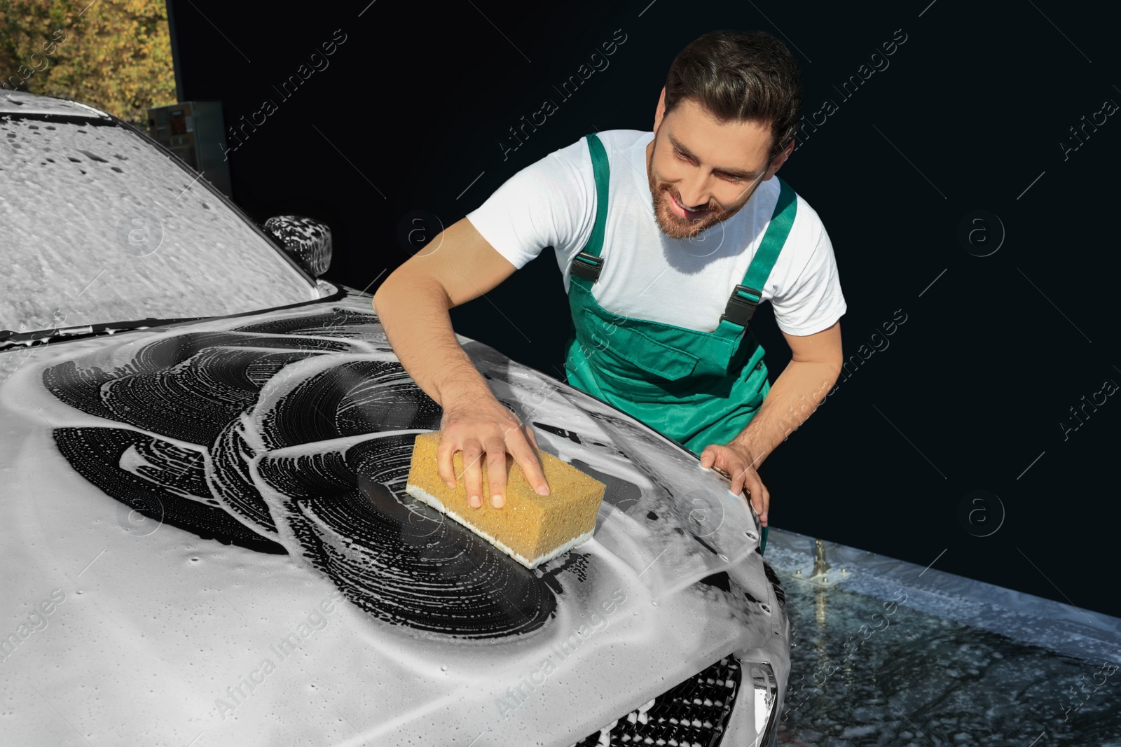 Photo of Worker washing auto with sponge at outdoor car wash