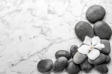 Stones and orchid flower on marble background, top view with space for text. Zen lifestyle