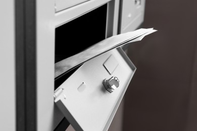 Open metal mailbox with envelopes indoors, closeup view