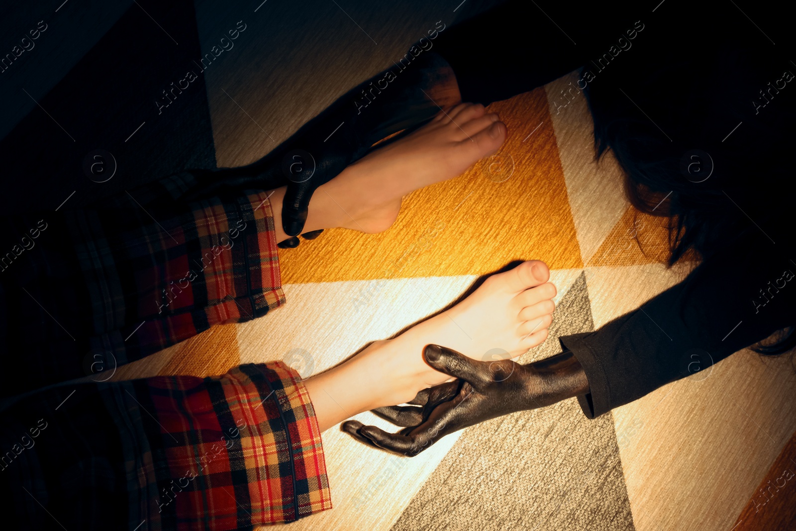 Photo of Scary monster under bed grabbing little girl by legs, top view