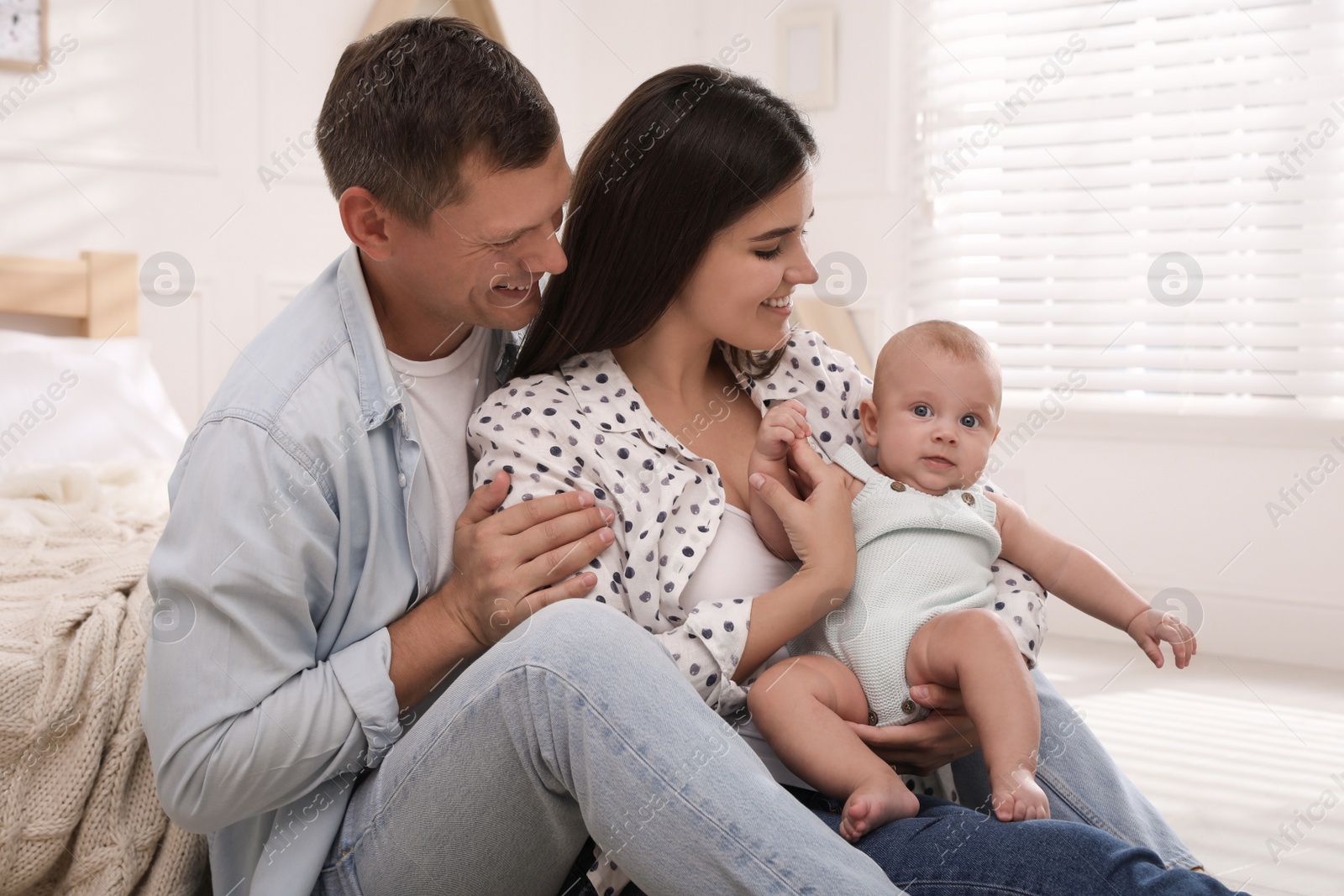 Photo of Happy family with their cute baby on floor in bedroom