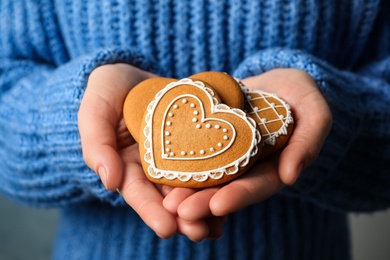 Photo of Woman holding tasty heart shaped gingerbread cookies, closeup