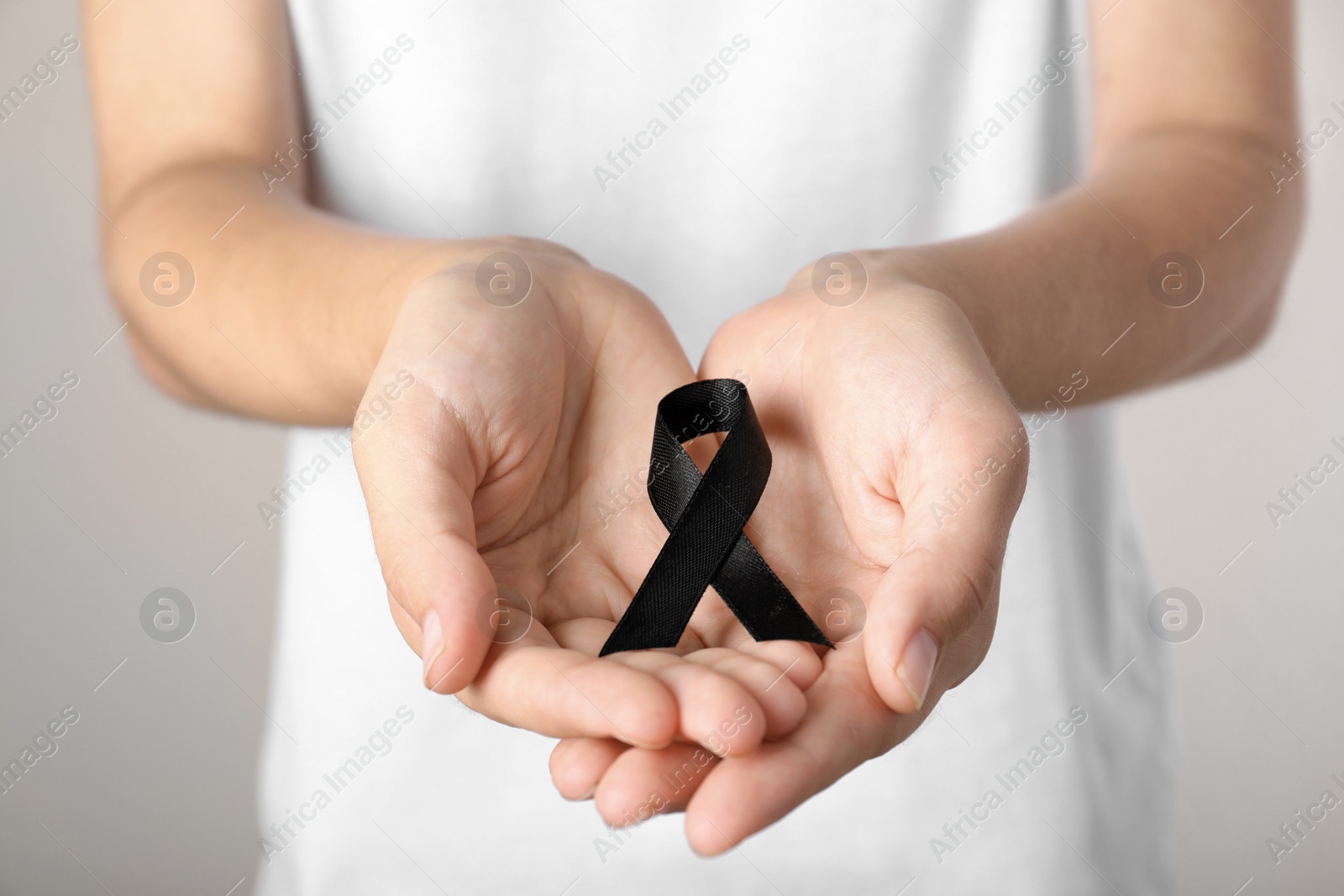 Photo of Young woman holding black ribbon, closeup. Funeral symbol