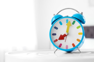 Colorful alarm clock on table in bedroom. Time to wake up