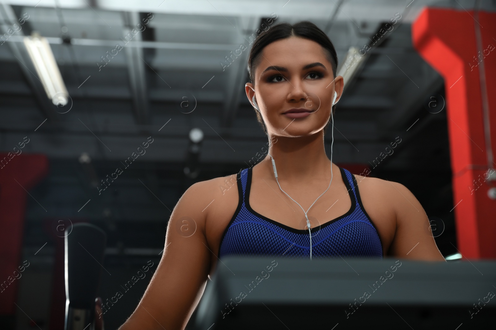 Photo of Young woman working out on elliptical trainer in modern gym