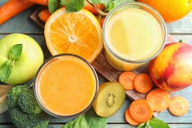 Glasses of delicious juices and fresh ingredients on blue table, flat lay