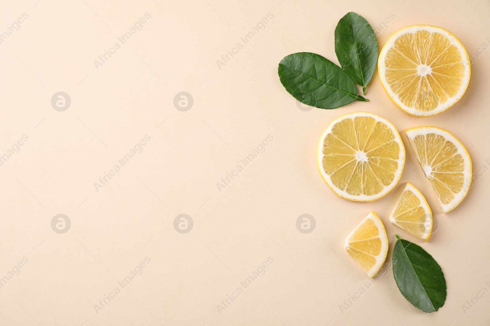 Photo of Fresh lemons and leaves on beige background, flat lay. Space for text