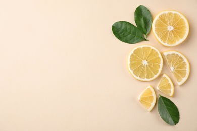 Fresh lemons and leaves on beige background, flat lay. Space for text