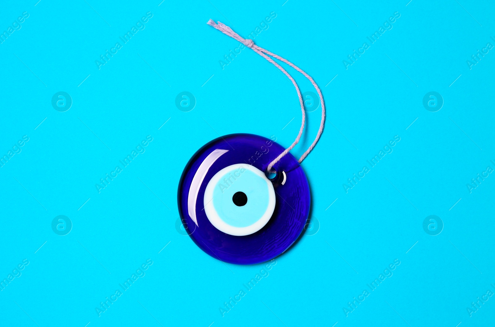 Photo of Evil eye amulet on light blue background, top view