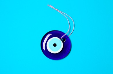 Evil eye amulet on light blue background, top view