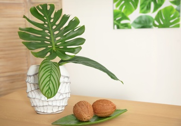 Vase with tropical leaves on table indoors. Interior design element