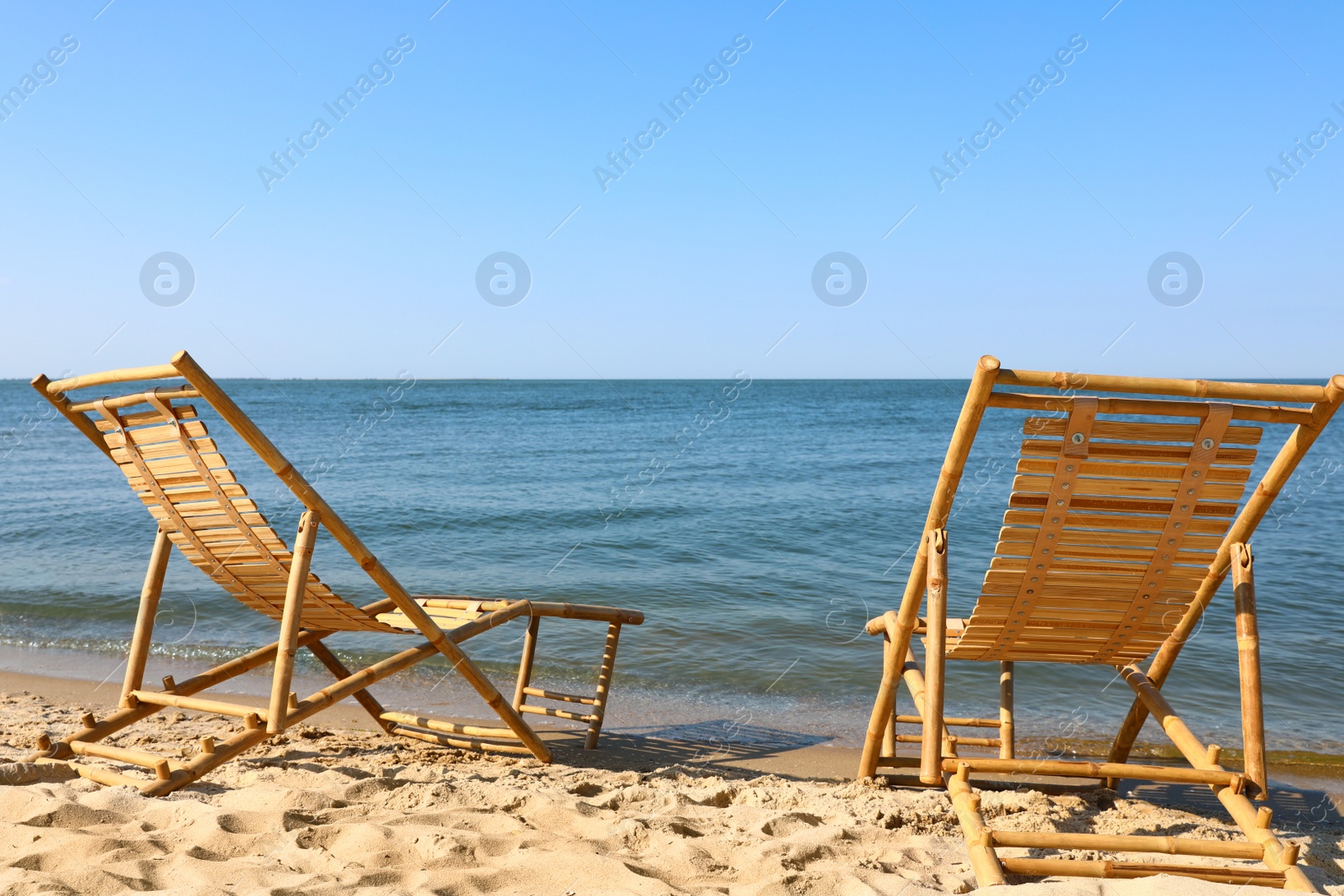 Photo of Sandy beach with empty wooden sunbeds on sunny day