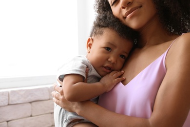 Photo of African-American woman with her baby at home. Happiness of motherhood