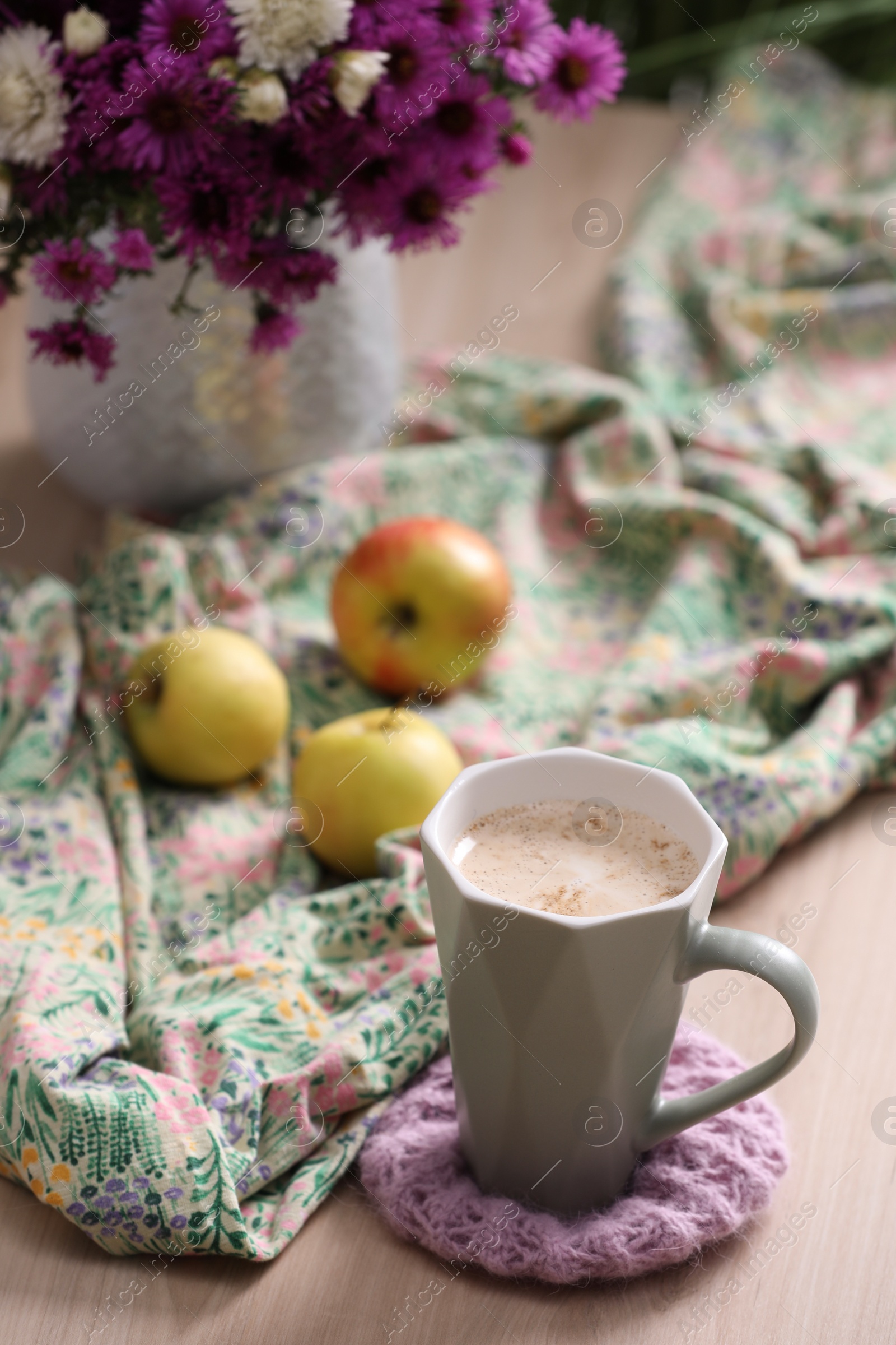 Photo of Cup of aromatic coffee, beautiful flowers and bright cloth on wooden table