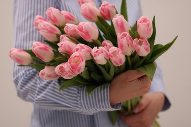 Photo of Woman with bouquet of beautiful fresh tulips on light grey background, closeup